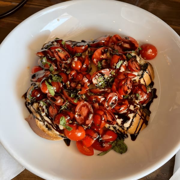 Oceanside Pizza's bruschetta appetizer with diced tomatoes, basil, and balsamic glaze on toasted bread.