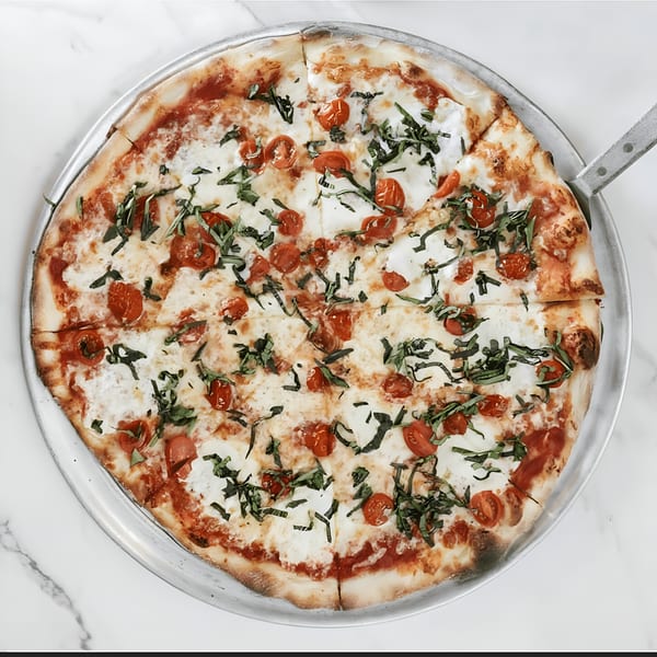 Oceanside Pizza's Margherita pizza with fresh mozzarella, cherry tomatoes, and basil on a metal pan.